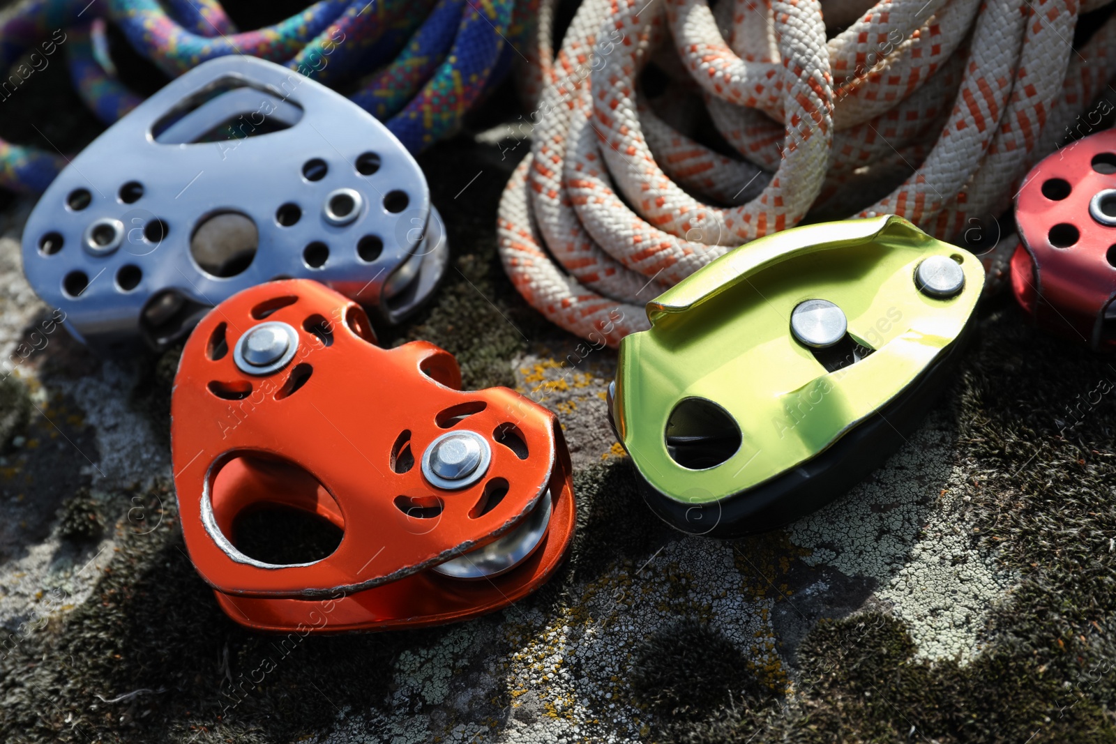 Photo of Different belay devices and ropes on rock, closeup. Climbing equipment