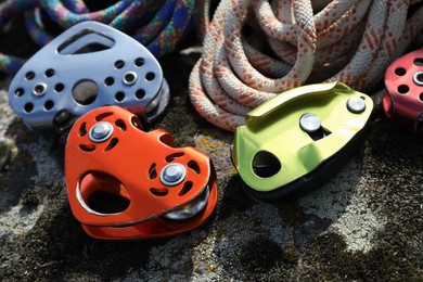 Different belay devices and ropes on rock, closeup. Climbing equipment