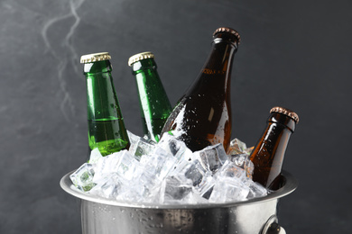 Photo of Metal bucket with bottles of beer and ice cubes on grey background