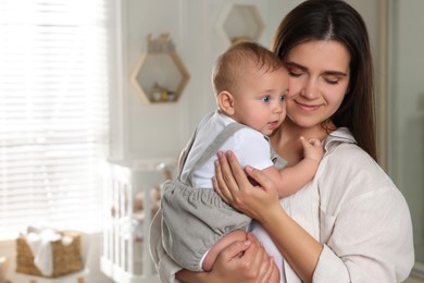 Photo of Happy young mother with her baby in nursery. Space for text