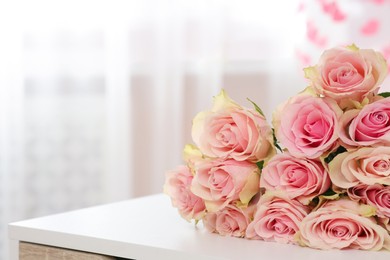 Photo of Beautiful bouquet of roses on white table, space for text. Happy birthday greetings
