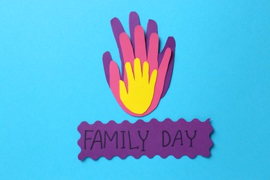 Photo of Card with text Family Day and paper palms on light blue background, flat lay