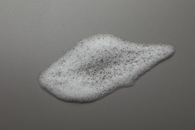 Smudge of fluffy soap foam on grey background, top view