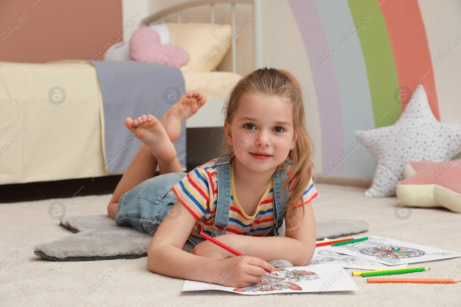Photo of Little girl coloring antistress page on floor indoors