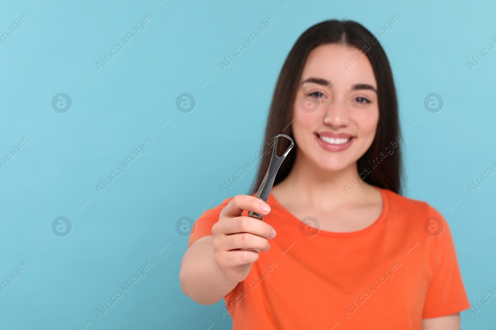 Photo of Happy woman with tongue cleaner on light blue background, selective focus. Space for text