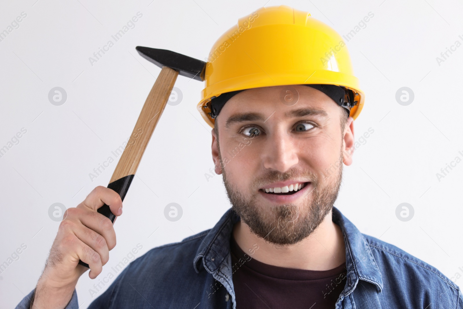 Photo of Funny young working man in hardhat with hammer on white background