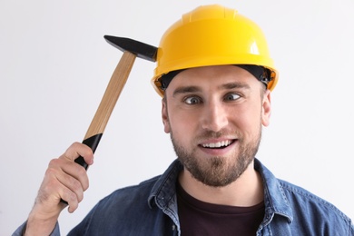Photo of Funny young working man in hardhat with hammer on white background