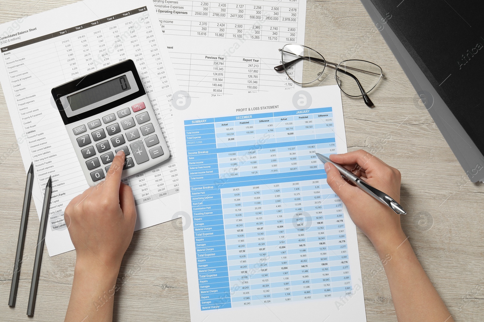 Photo of Woman making calculations on calculator at wooden table, top view