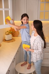 Photo of Mother and daughter cleaning up kitchen together at home