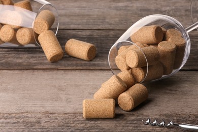 Glasses with wine corks and corkscrew on wooden table