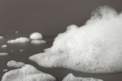 Fluffy bath foam on grey background, closeup