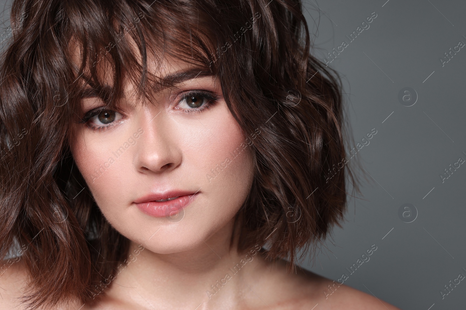 Photo of Beautiful young woman with wavy hairstyle on grey background