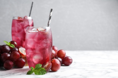 Photo of Delicious grape soda water with mint and berries on white marble table, space for text. Refreshing drink