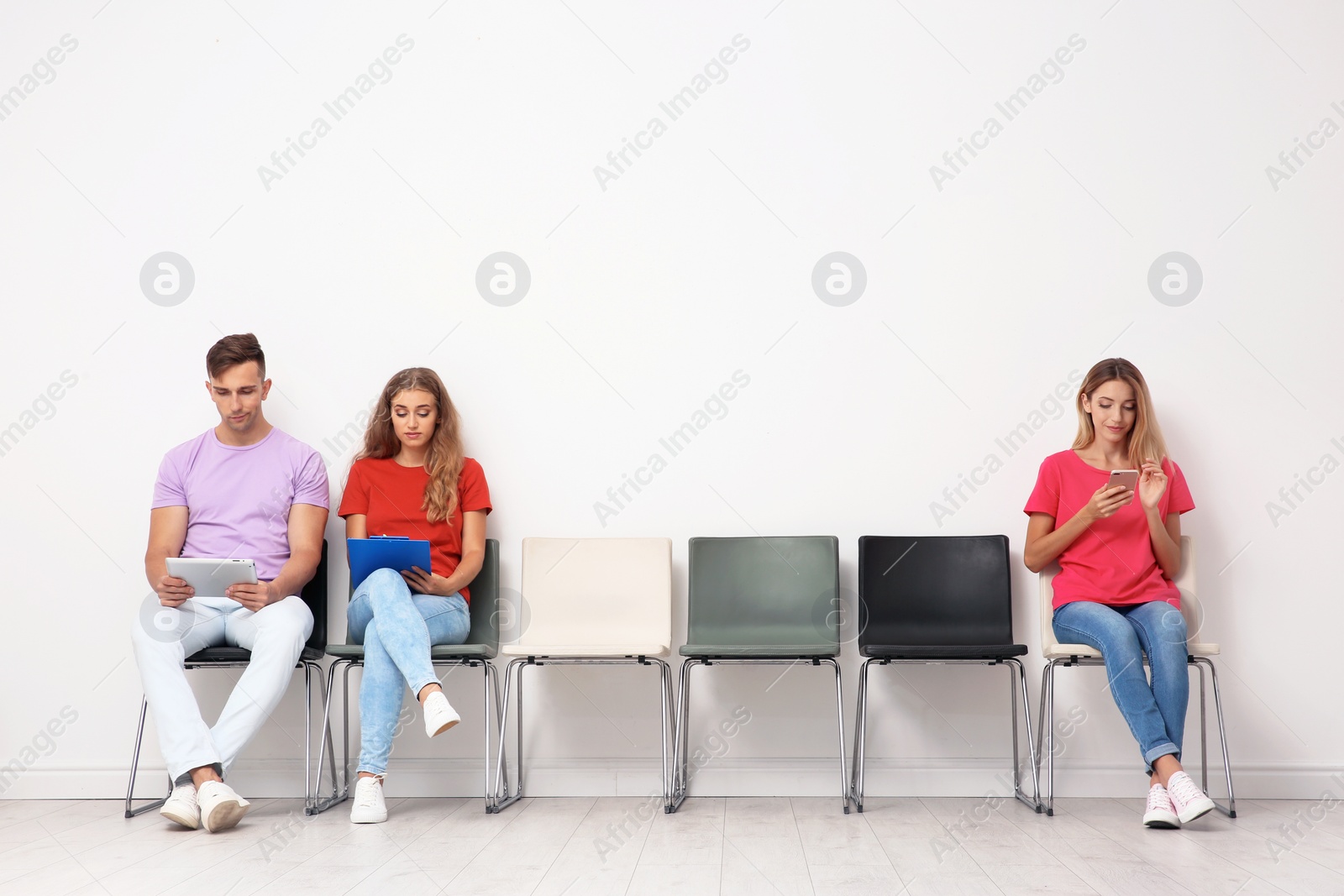 Photo of Group of young people waiting for job interview near light wall