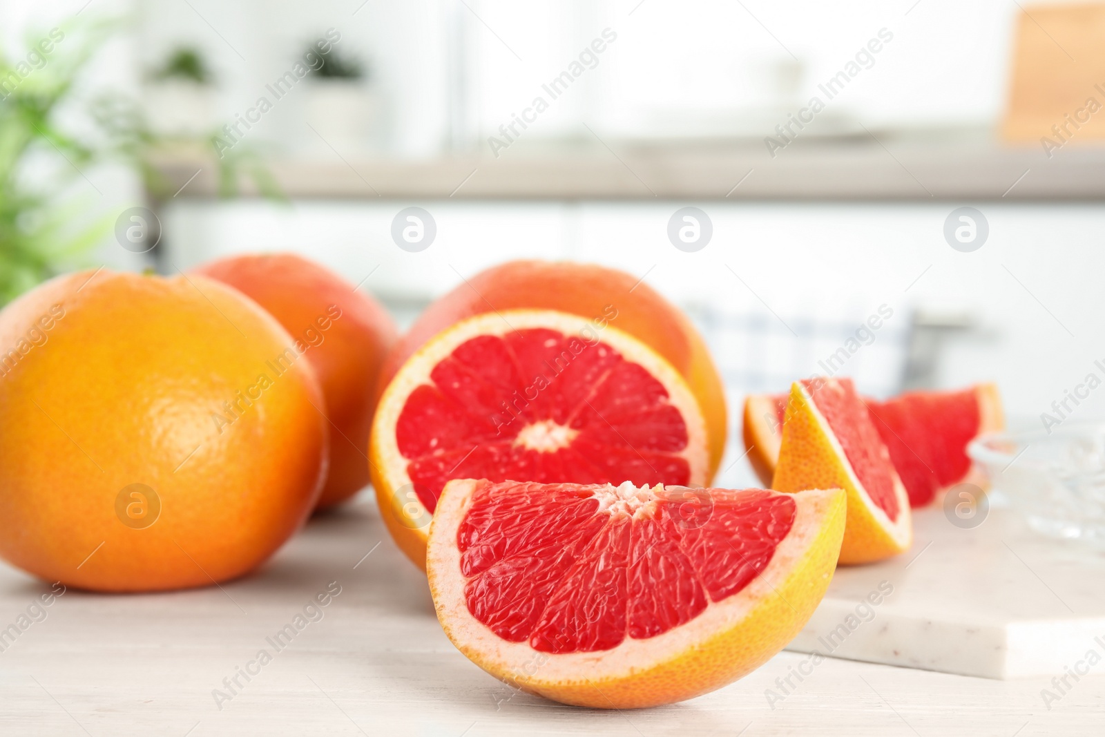 Photo of Cut and whole grapefruits on table against blurred background