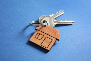 House keys with trinket on color background