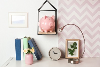 Photo of Cute piggy bank on shelf indoors. Stylish interior element