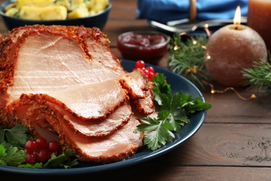 Delicious Christmas ham served with garnish on wooden table, closeup