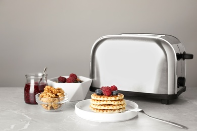 Photo of Delicious breakfast with waffles and berries served on light marble table against grey background