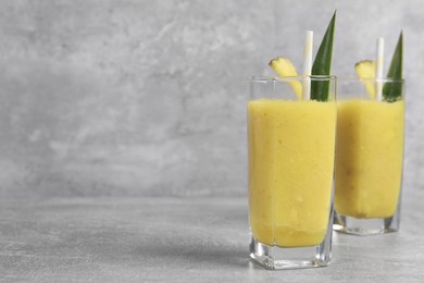 Photo of Tasty pineapple smoothie on light gray table, space for text
