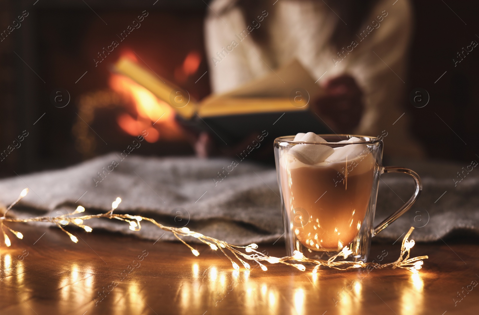 Photo of Delicious sweet cocoa and blurred woman with book on background