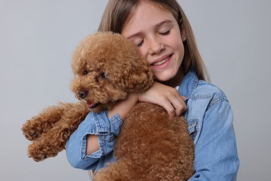 Photo of Little child with cute puppy on light grey background. Lovely pet