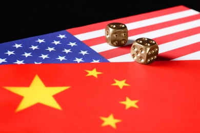 Photo of USA and China flags with dices on black table. International relations