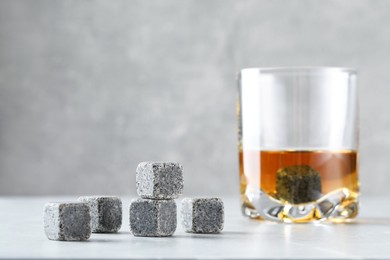 Whiskey stones and drink in glass on light table, closeup