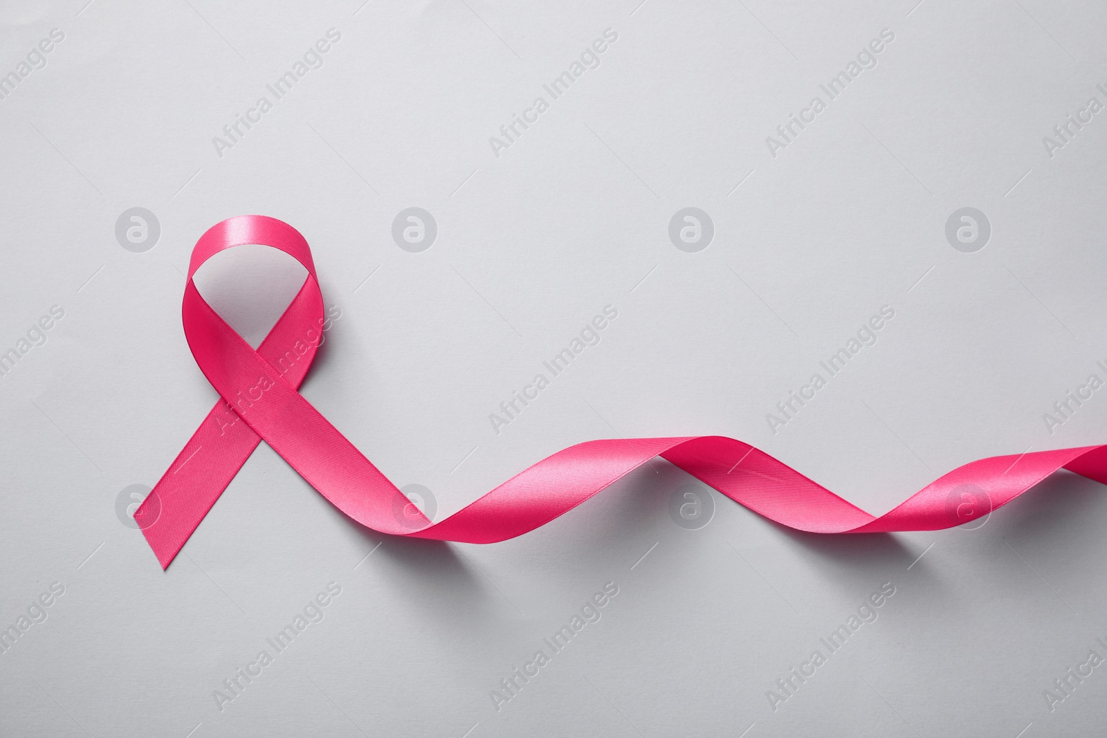 Photo of Pink ribbon on light grey background, top view. Breast cancer awareness concept