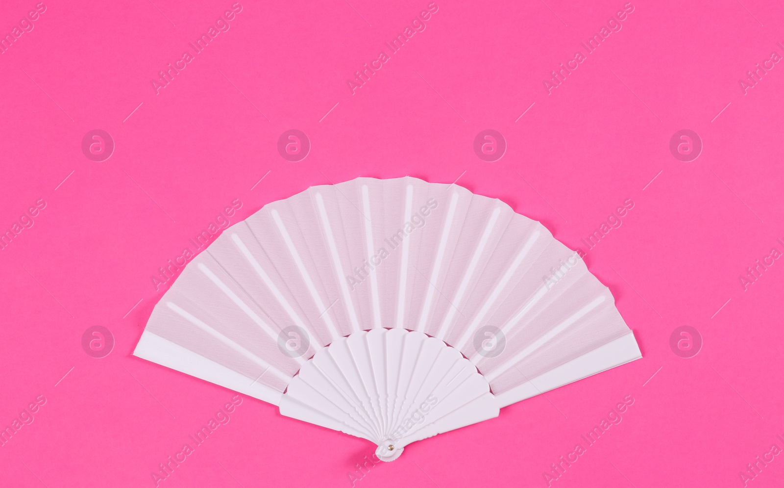 Photo of White hand fan on pink background, top view