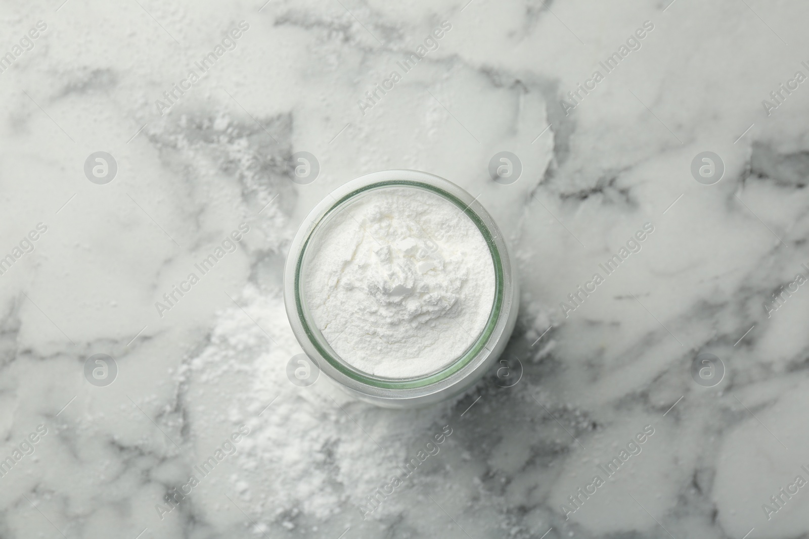 Photo of Baking powder in jar on white marble table, top view