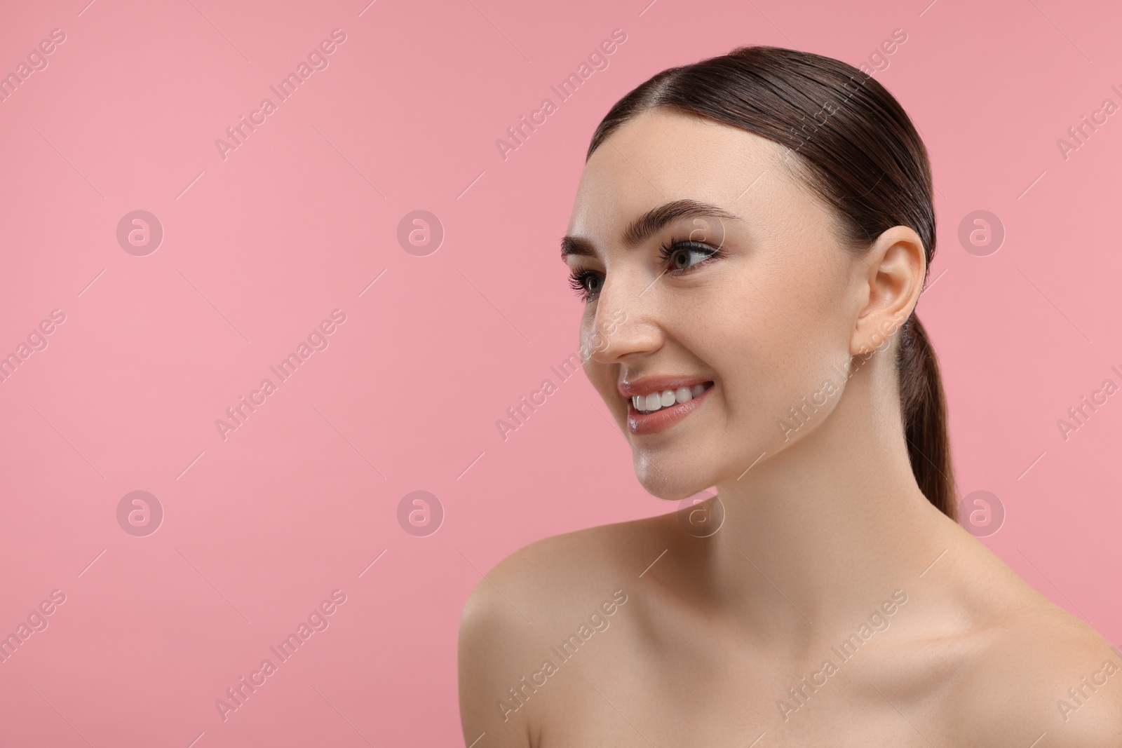 Photo of Portrait of smiling woman on pink background. Space for text