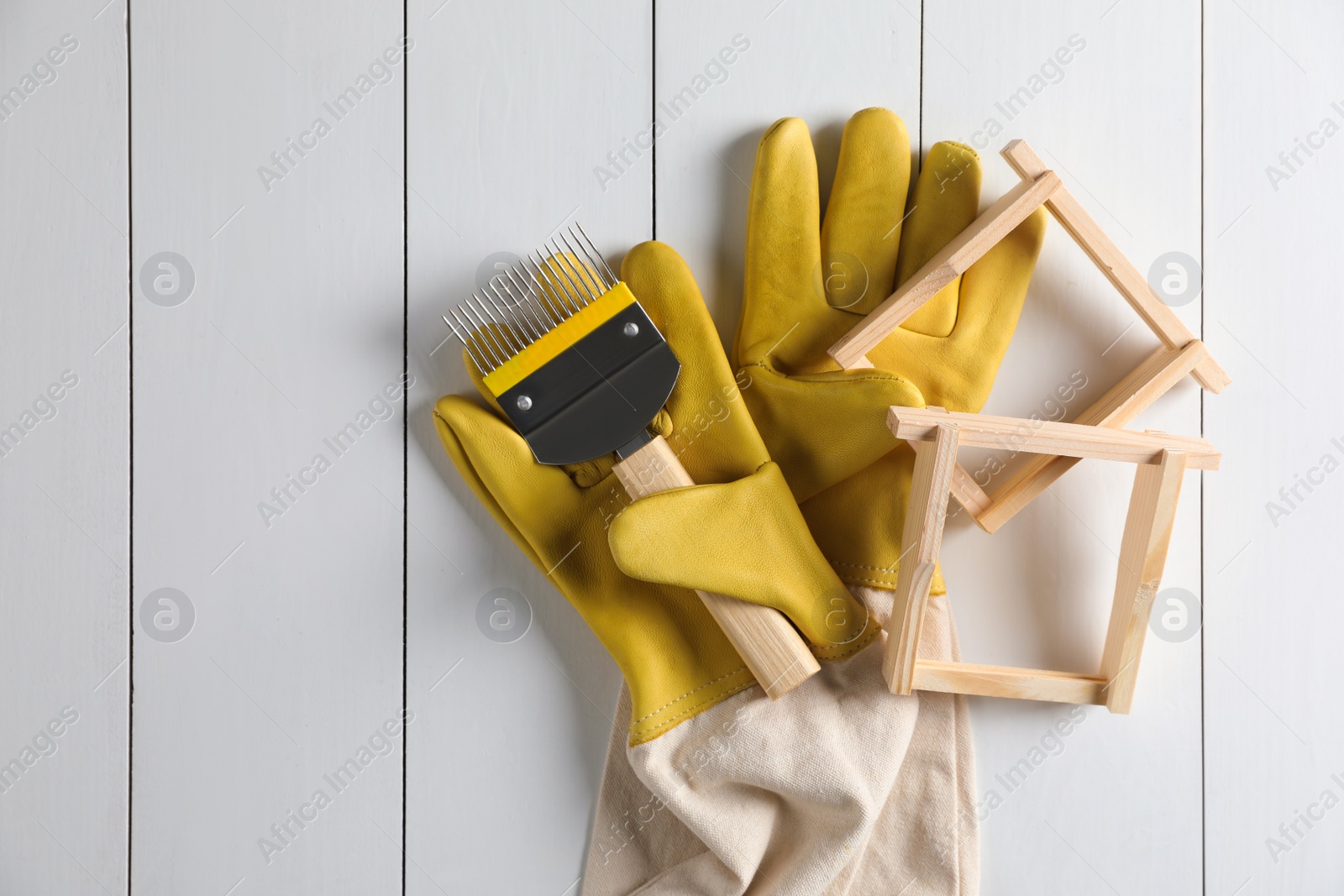 Photo of Honeycomb frames and beekeeping tools on white wooden table, flat lay. Space for text