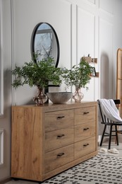 Photo of Modern bathroom interior with stylish mirror, eucalyptus branches, vessel sink and wooden vanity