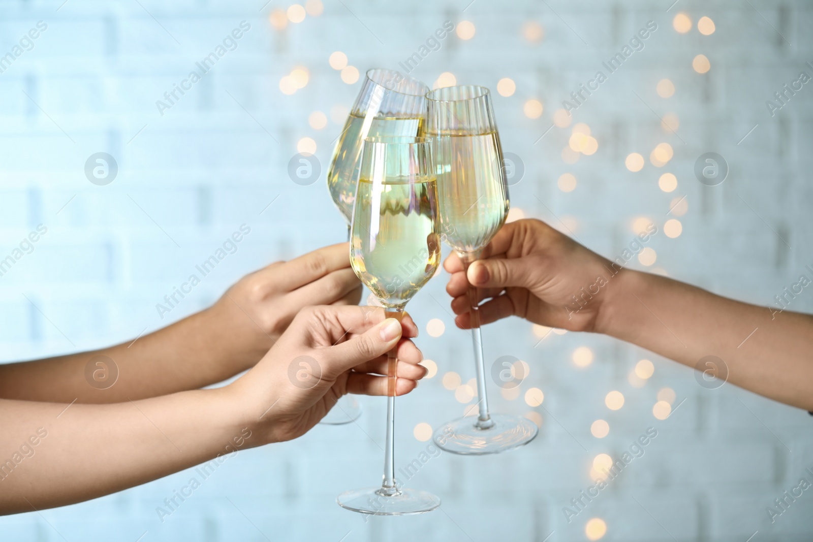 Photo of People clinking glasses of champagne against blurred lights, closeup