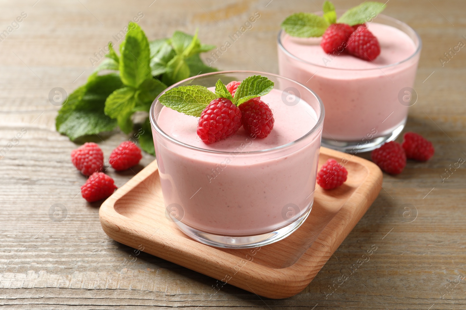 Photo of Delicious raspberry mousse with mint on wooden table