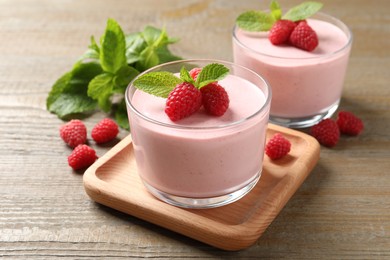 Photo of Delicious raspberry mousse with mint on wooden table