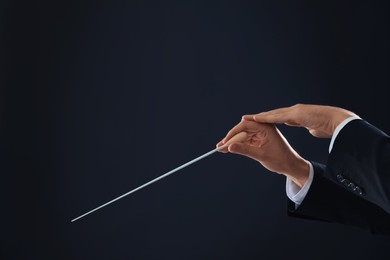 Photo of Professional conductor with baton on black background, closeup. Space for text