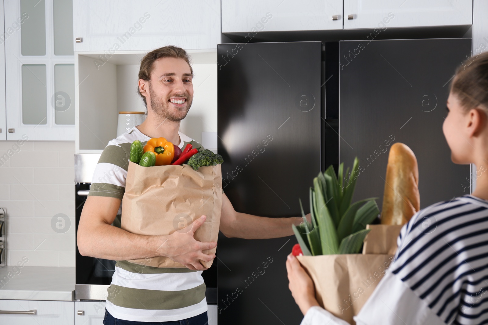 Photo of Couple with fresh products near refrigerator in kitchen