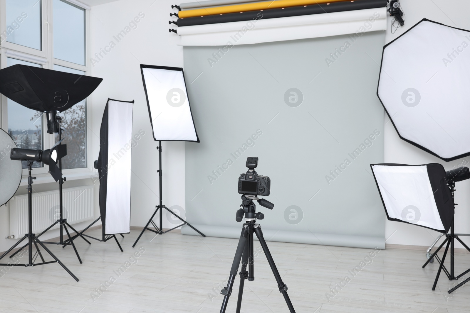 Photo of Camera on tripod and professional lighting equipment in modern photo studio