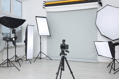 Camera on tripod and professional lighting equipment in modern photo studio