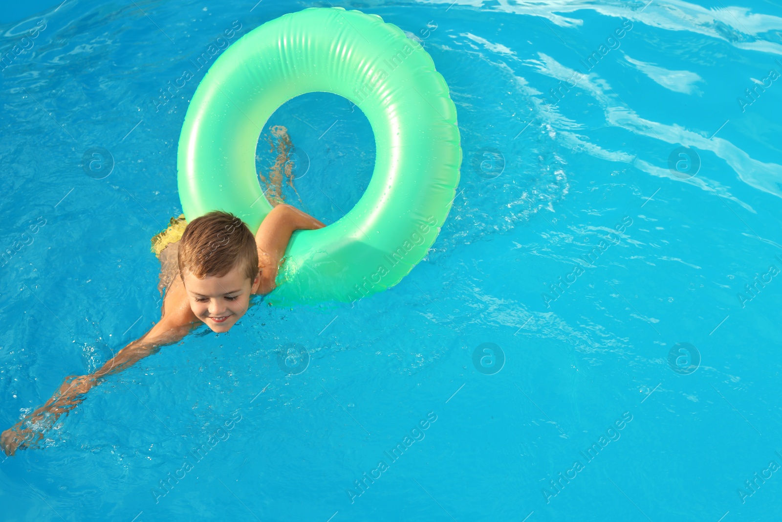 Photo of Little child with inflatable ring in outdoor swimming pool. Dangerous situation