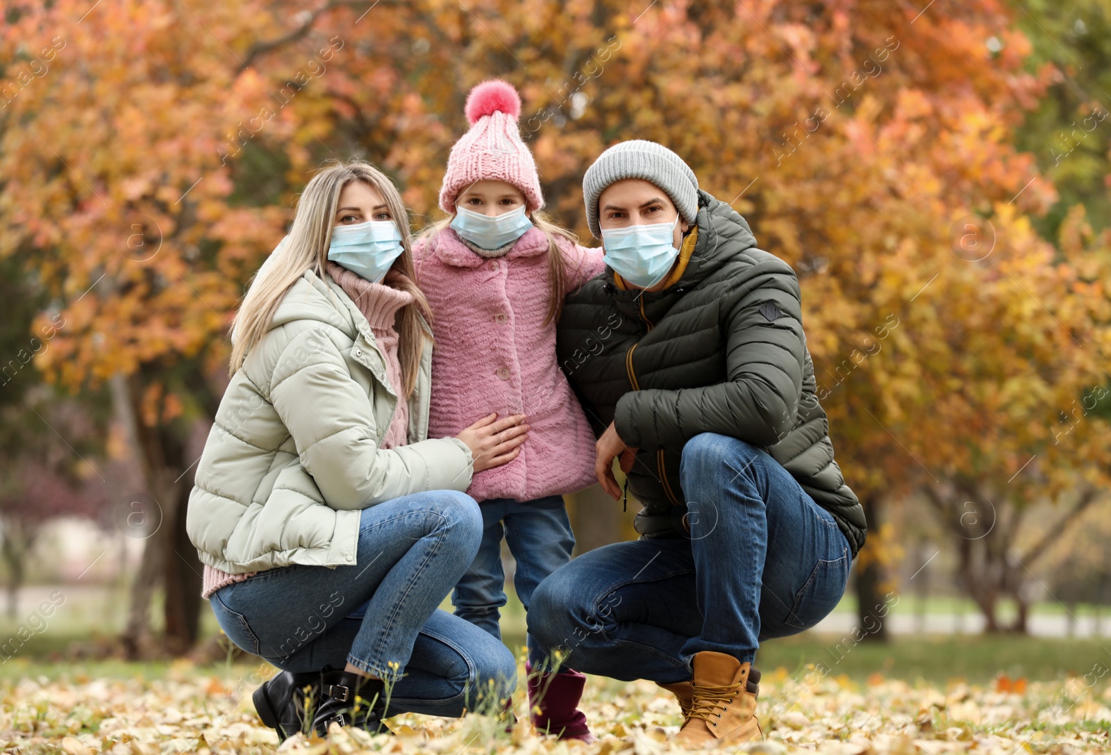 Photo of Family in medical masks outdoors on autumn day. Protective measures during coronavirus quarantine