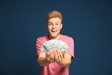 Photo of Portrait of happy lottery winner with money fan on blue background