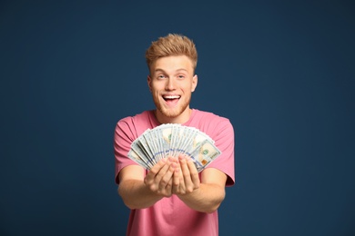 Portrait of happy lottery winner with money fan on blue background