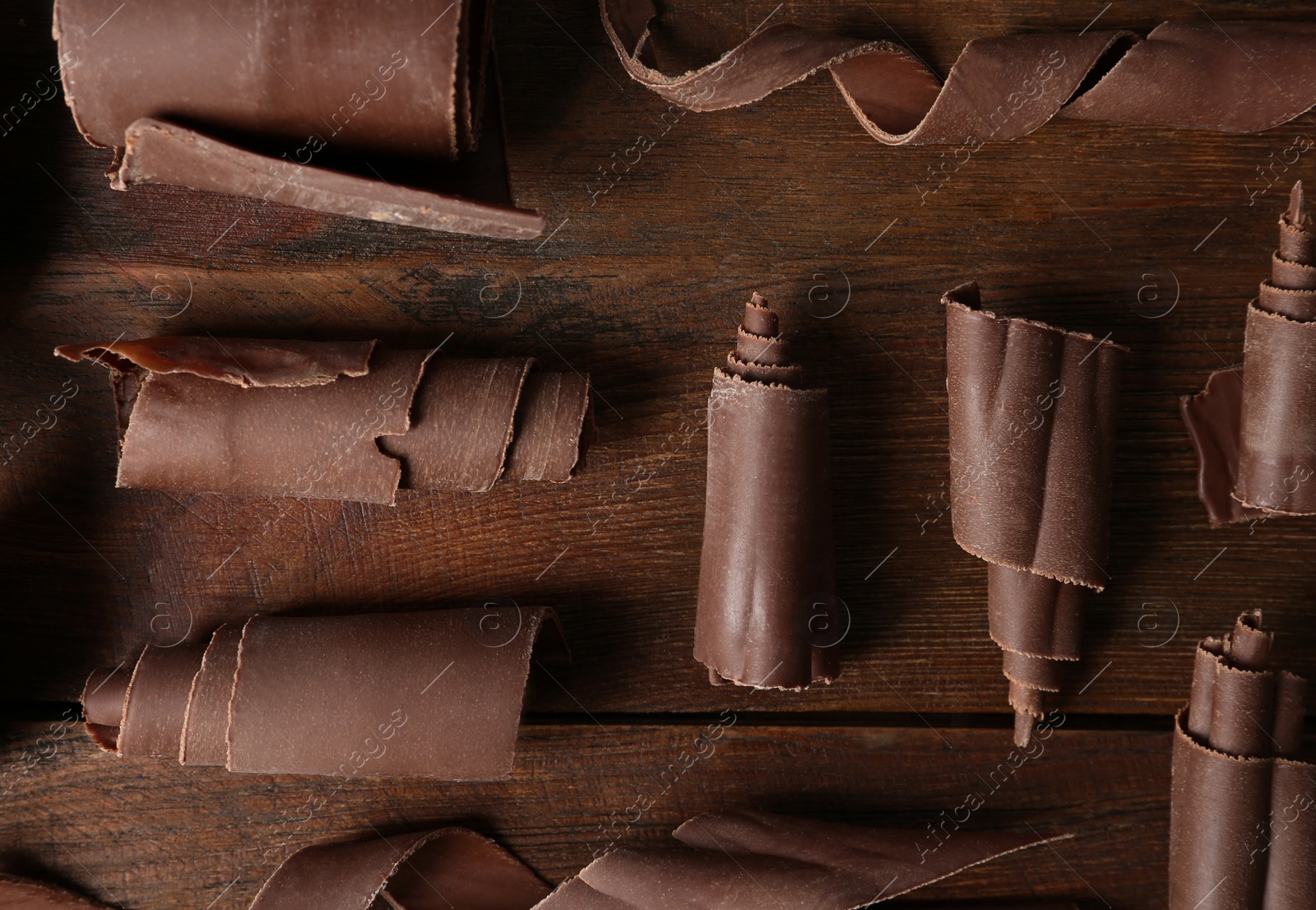 Photo of Chocolate curls on wooden background, flat lay