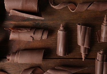 Photo of Chocolate curls on wooden background, flat lay