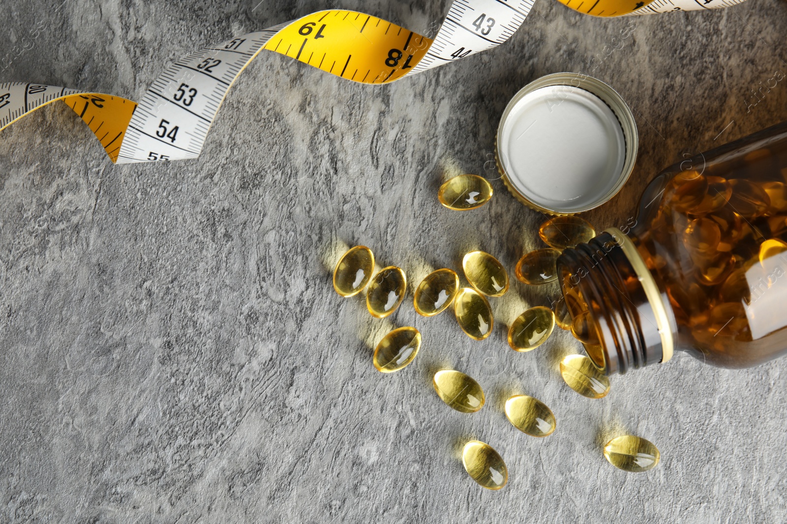 Photo of Cod liver oil pills with measuring tape and space for text on gray background, flat lay