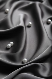 Photo of Many beautiful pearls on delicate black silk, closeup