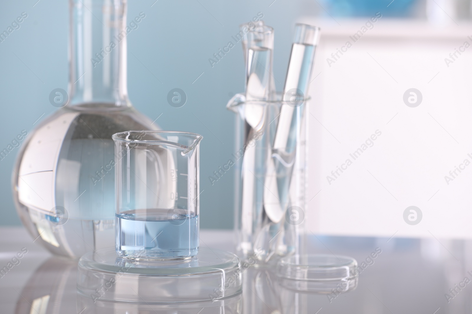 Photo of Laboratory analysis. Different glassware with liquid on white table against blurred background